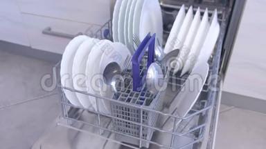 清洁厨房内置<strong>洗碗机篮</strong>子中的白色盘子和<strong>餐具</strong>。